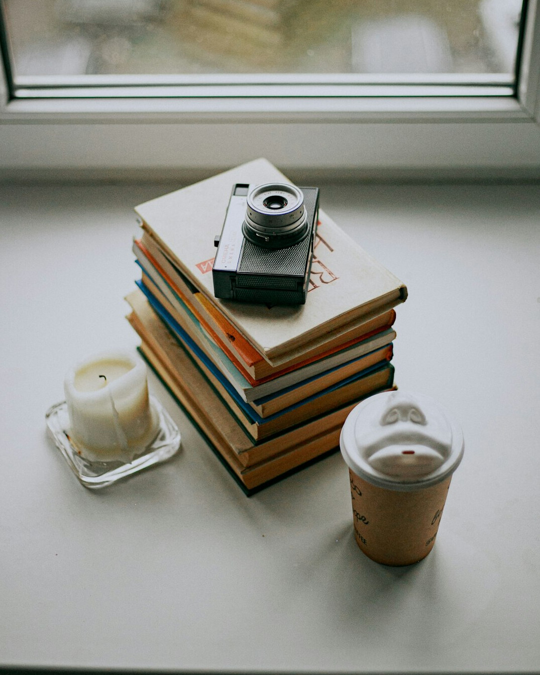 Stack of books next to a laptop and cup of coffee